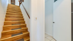 Un escalier en bois, doté d’une rampe, mène à une porte blanche.