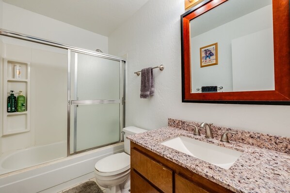 A bathroom with a glass-enclosed shower, a white toilet, a sink with a granite countertop, and a large mirror with a wooden frame. - Quaking Aspen Condo 2 Bedroom Condo (Stateline)