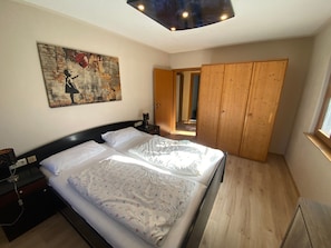 Ein Schlafzimmer mit zwei Betten, einem Holzschrank, einem Bild an der Wand und einem Fenster.