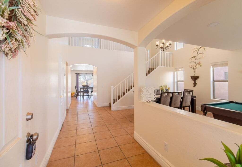 A spacious hallway with a pool table, a staircase, and a dining area.