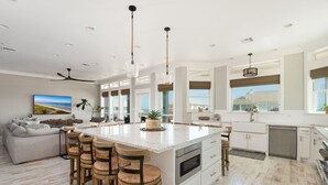 A spacious kitchen with a large island, bar stools, and modern appliances. - Casa Del Sol 4 Bedroom Home (Port Bolivar)