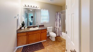 A bathroom with a vanity, sink, mirror, toilet, shower curtain, and a rug. - 106 Middlebrook Dr, Cartersville (Cartersville)