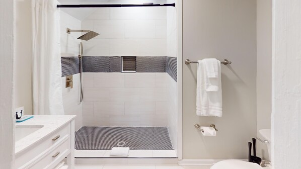 A modern bathroom with a glass-enclosed shower, a white sink, and a toilet.