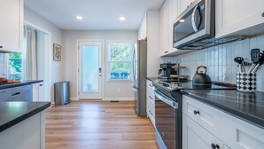 A modern kitchen with white cabinets, stainless steel appliances, and a wooden floor. - 18 Huntcliff Dr, Cartersville (Cartersville)