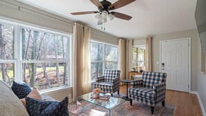 A spacious living room with large windows, a ceiling fan, and a coffee table.
