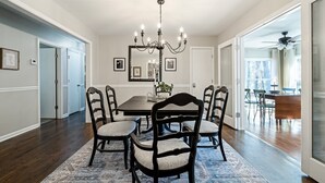 A dining room with a dark wooden table, four chairs, a chandelier, and a patterned rug.