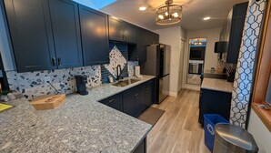 A modern kitchen with dark cabinets, granite countertops, a built-in oven, and a skylight.