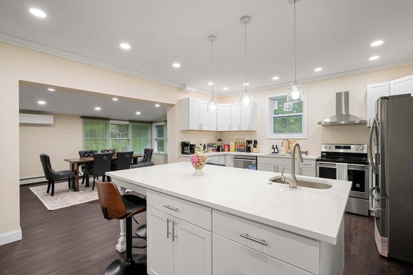 A modern kitchen with white cabinets, stainless steel appliances, and pendant lighting.