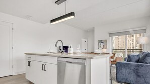 Uma cozinha moderna com máquina de lavar louça, uma sala de jantar com mesa e cadeiras e uma sala de estar com sofá.