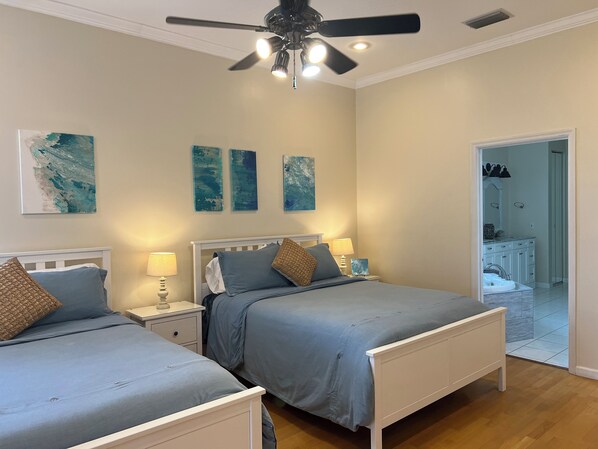 Un dormitorio con dos camas, ventilador de techo y una obra de arte en la pared.