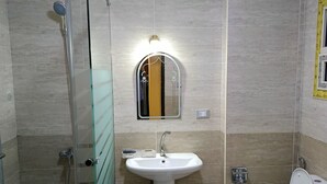A bathroom with a glass shower enclosure, a pedestal sink, a toilet, and a washing machine. - THE MESSAHA ROYALE (Giza Governorate)