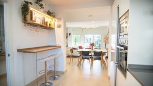 A modern kitchen with a bar area, dining table, and chairs.