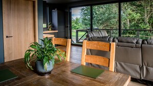 Un comedor moderno con una mesa de madera, dos sillas, una planta en maceta y un sofá con cojines de cuero.