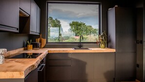Una cocina moderna con un amplio ventanal, muebles oscuros y encimera de madera.