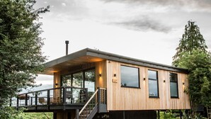 Una casa moderna de madera con balcón, una escalera que conduce a la entrada y un camino de grava.