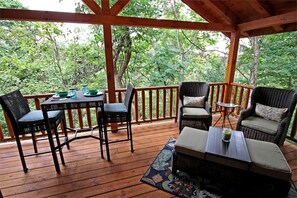 Una terraza de madera con muebles de mimbre, una mesa y sillas.