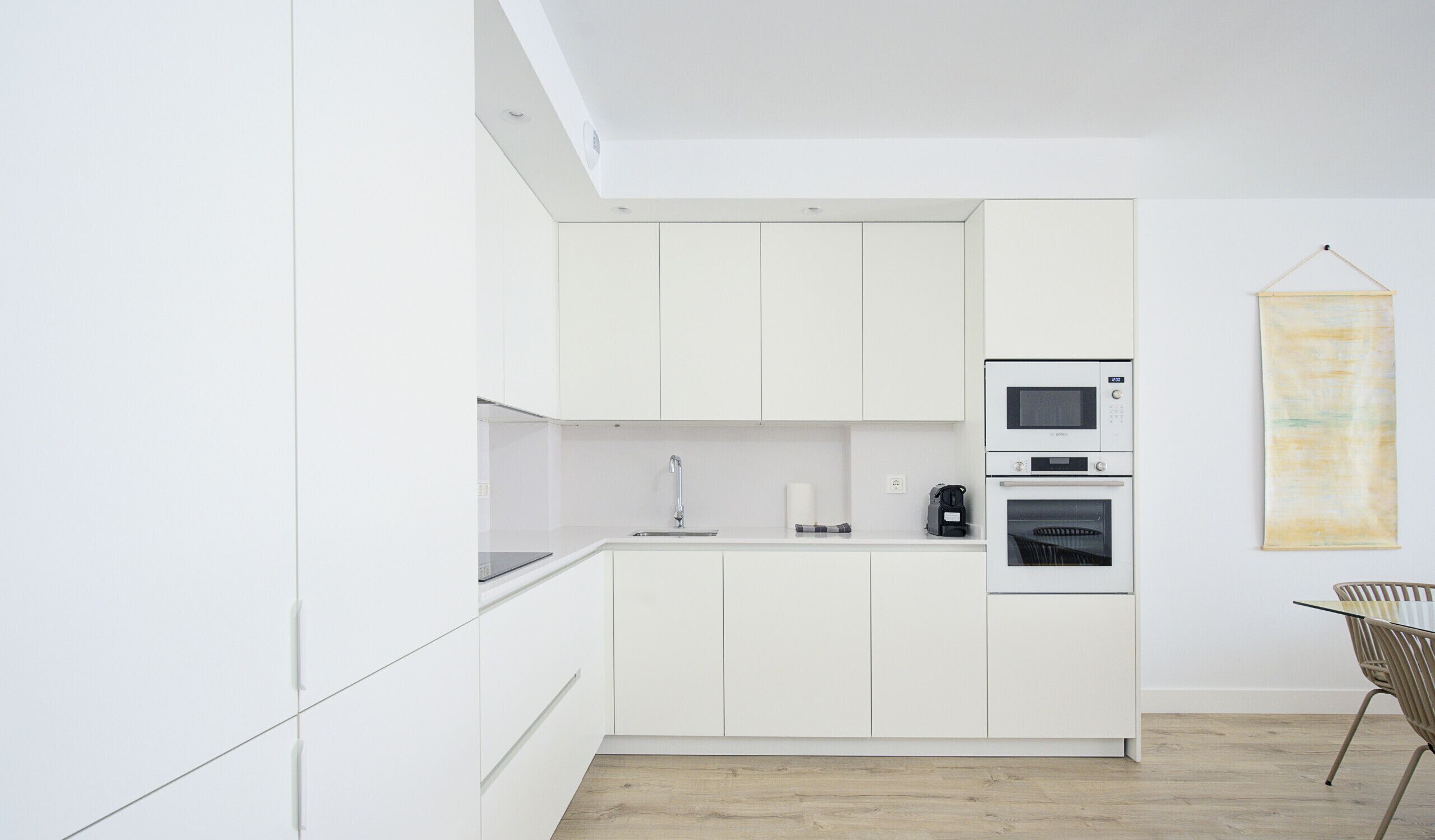 Una cucina moderna con mobili bianchi, un forno a microonde, un forno e una macchina per il caffè.