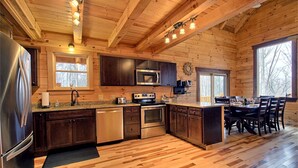 L’intérieur d’un chalet en bois comprend une cuisine équipée d’un réfrigérateur, d’un four à micro-ondes, d’une cuisinière et d’un évier.