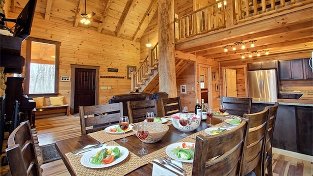 L’intérieur d’une cabane en bois comprend un coin repas, un escalier et une cuisine.