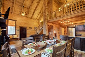 A wooden cabin interior with a dining area, a staircase, and a kitchen. - Charming Vacation Cabin Secluded in the Woodlands near Old Man's Cave, Ohio (Logan)