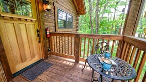 A wooden cabin with a porch, a table with blue mugs, and a fire extinguisher. - Wonderful Ohio Vacation Rental for Nature Getaways near Hocking Hills Park (Logan)