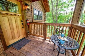 A wooden cabin with a porch, a table with blue mugs, and a fire extinguisher.
