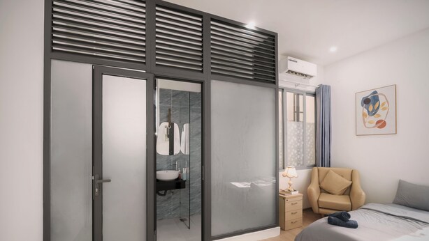 A modern bedroom with a bed, a chair, a bedside table, a wardrobe, and a bathroom with a sink and mirror. - Healing home I 3 minutes ride to the Beach I Garden & BBQ (Đà Nẵng)
