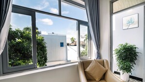 A room with a large window, a beige sofa, and a potted plant. - Healing home I 3 minutes ride to the Beach I Garden & BBQ (Đà Nẵng)
