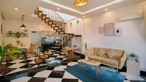 A modern living room with a black and white checkered floor, a staircase, a sofa, and a coffee table. - Healing home I 3 minutes ride to the Beach I Garden & BBQ (Đà Nẵng)