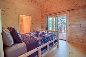 A wooden cabin bedroom with a bed, pillows, and a view of the outdoors. - Stately Log Cabin with a Hot Tub Perfect for a Weekend Getaway near Columbus, Ohio (Logan)