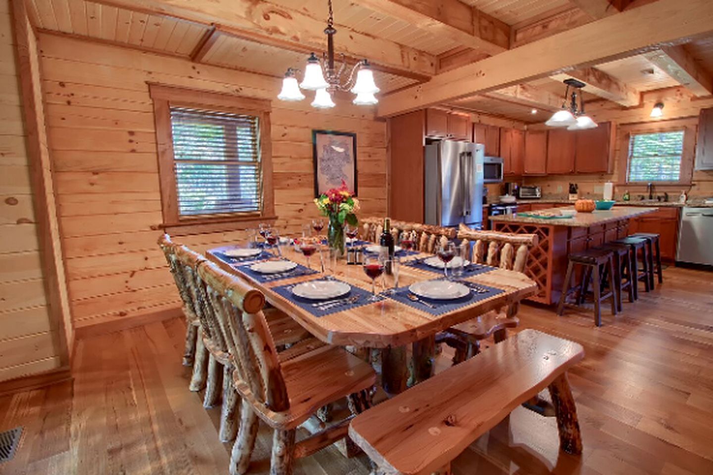 A wooden cabin interior with a dining area, kitchen, and bar.