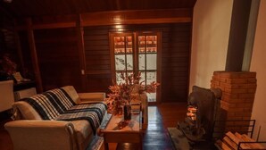 A cozy living room with a sofa, a coffee table, and a fireplace. - Pousada dos Quatis (Campos do Jordão)