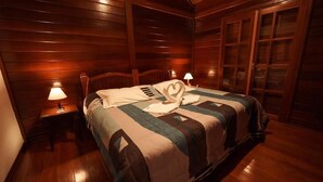 A wooden-paneled room with a bed, two bedside lamps, and a window with blinds. - Pousada dos Quatis (Campos do Jordão)