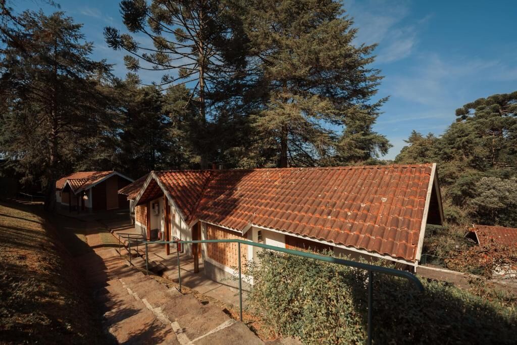 A row of rustic cabins with red-tiled roofs, surrounded by dense pine trees.