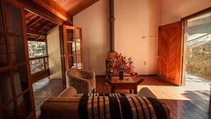 A cozy room with a wooden ceiling, a fireplace, a sofa, and a dining table. - Pousada dos Quatis (Campos do Jordão)