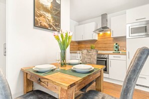 A dining area with a wooden table, chairs, and a vase of flowers.