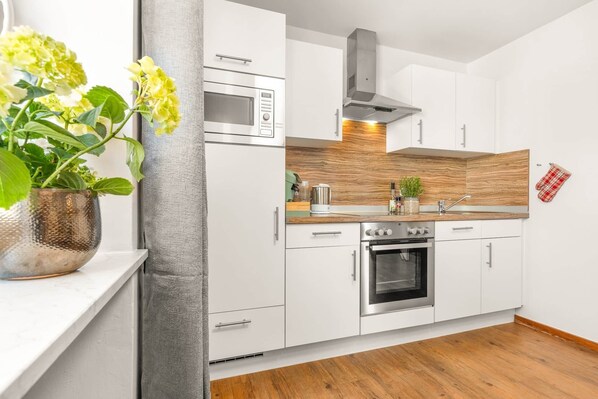 A modern kitchen with white cabinetry, a built-in oven, and a microwave.