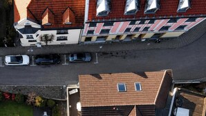 Vista aérea de un barrio residencial con varias casas, una calle y automóviles estacionados.