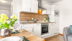 Una cocina moderna con armarios blancos, un horno de acero inoxidable y un microondas.