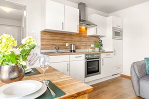 Una cocina moderna con armarios blancos, un horno de acero inoxidable y un microondas.