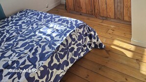 Un dormitorio con un armario de madera, una cama con cubrecama estampado y un equipo de aire acondicionado en la pared.