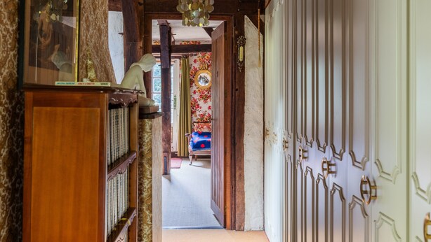 A hallway with a wooden bookshelf, a mirror, and a door with decorative panels.