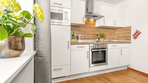 Una cocina moderna con armarios blancos, horno empotrado y microondas.