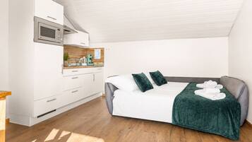 Ein modernes Schlafzimmer mit Bett, einer Küchenzeile und Holzboden.