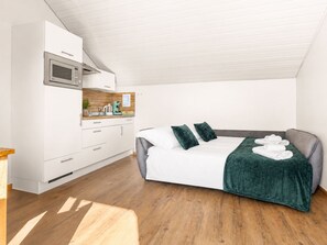 Ein modernes Schlafzimmer mit Bett, einer Küchenzeile und Holzboden.