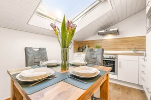 A modern kitchen with white cabinets, a wooden countertop, and a dining area with a wooden table and chairs.