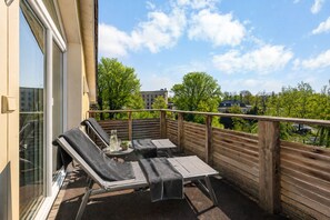 A balcony with two lounge chairs, a small table, and a bottle.