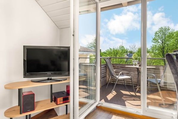A balcony with a TV, a table, and chairs.