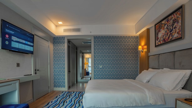 Een moderne hotelkamer met een groot bed, een bureau en een televisie waarop een Netflix-interface te zien is.