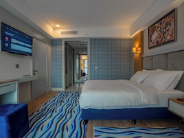 A modern hotel room with a large bed, a desk, and a television displaying a Netflix interface.